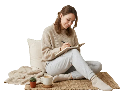 Woman writing in a notebook while sitting on a rug