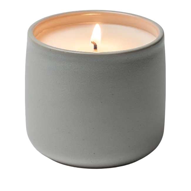 Lit scented candle in a grey ceramic jar